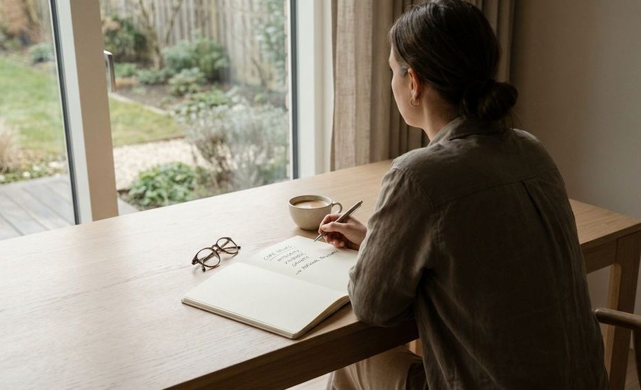 Person writing core values in a notebook to develop a personal philosophy for decisions